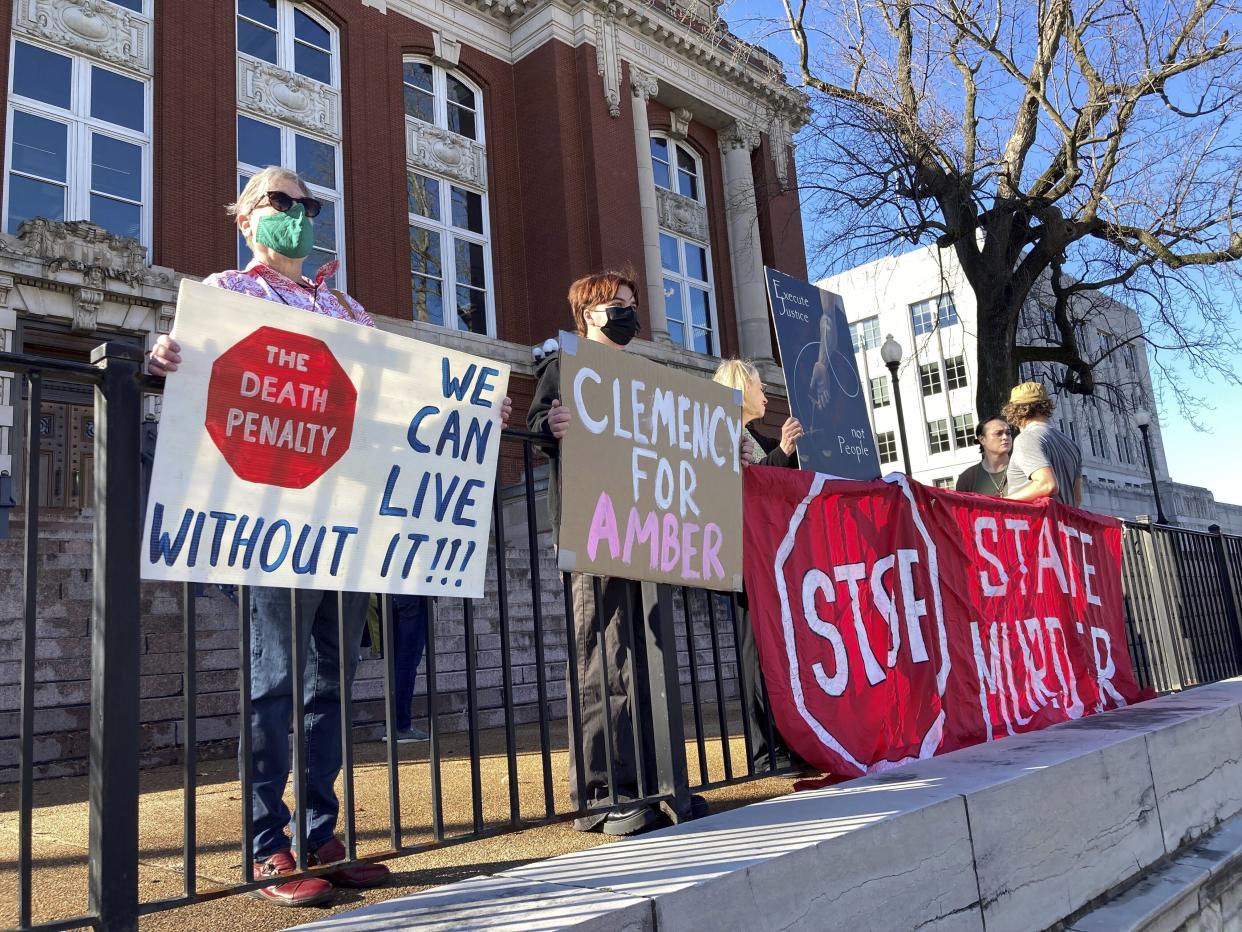 Sue Gibson, left, of Jefferson City, and Jay Castilow, of Columbia, hold signs along with others outside the Missouri Supreme Court building while protesting the execution of Amber McLaughlin on Tuesday, Jan. 3, 2023, in Jefferson City, Mo. McLaughlin was convicted of killing Beverly Guenther in 2003. (AP Photo/David A. Lieb)