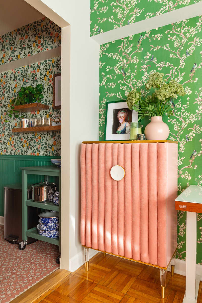 Framed portrait next to floral vase on top of a fabric dresser.