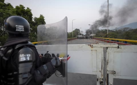 A Colombian police officer in Cucuta, Colombia, looks across the border at Venezuelan security forces  - Credit: RAUL ARBOLEDA/AFP/Getty Images