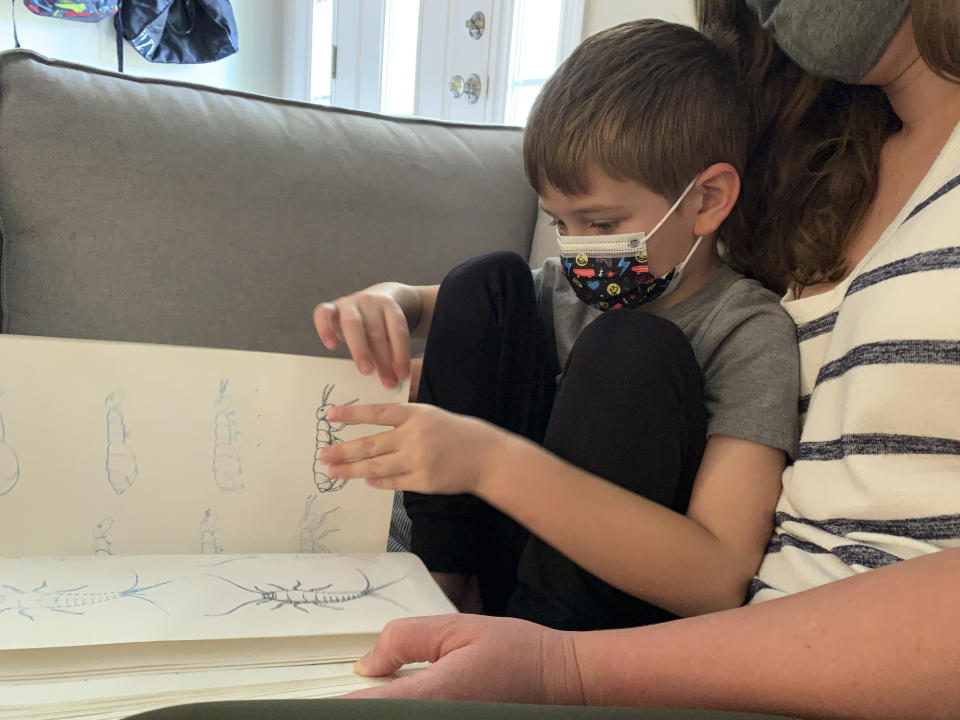 Five-year-old Berkeley Goss reads through his favorite book about bugs inside his Monroe, N.C. home. His parents, Jeff and Emily Goss chose to pull him out of the Union County School District where he had attended the first week of in-person kindergarten fearing the lack of mask requirements would lead to a COVID-19 infection for Berkeley or his at-risk family members. (AP Photo/Sarah Blake Morgan)