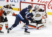 Anaheim Ducks goaltender John Gibson, right, saves a shot by Winnipeg Jets' David Gustafsson (19) as Ducks' William Lagesson, left, defends during second-period NHL hockey game action in Winnipeg, Manitoba, Friday, March 15, 2024. (John Woods/The Canadian Press via AP)