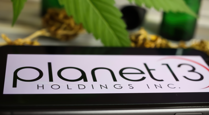 Closeup of mobile phone screen with logo lettering of cannabinoid company planet 13 (PLNHF) holding, blurred marijuana leaf (selective focus on lower part of letter a)