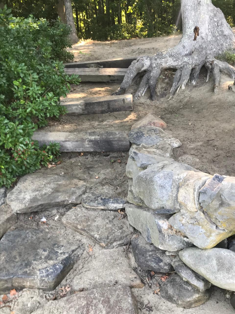 Flat stepping stones and short railroad ties form a set of stairs to a sandy beach on the Narrow River.