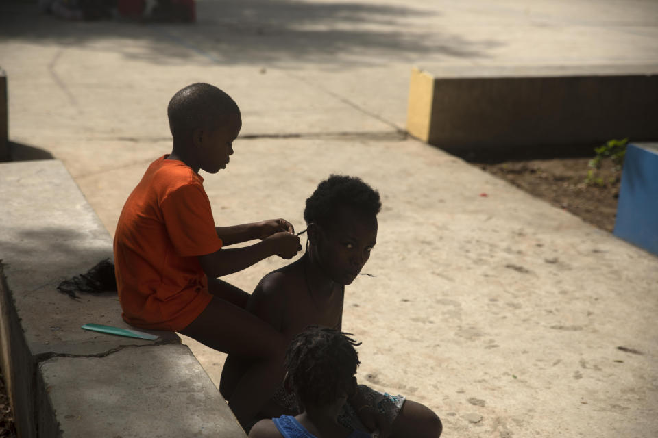 A boy braids a girl's hair in a school turned into a shelter for families forced to leave their home in Cite Soleil due to clashes between armed gangs, in Port-au-Prince, Haiti, Saturday, July 23, 2022. (AP Photo/Odelyn Joseph)