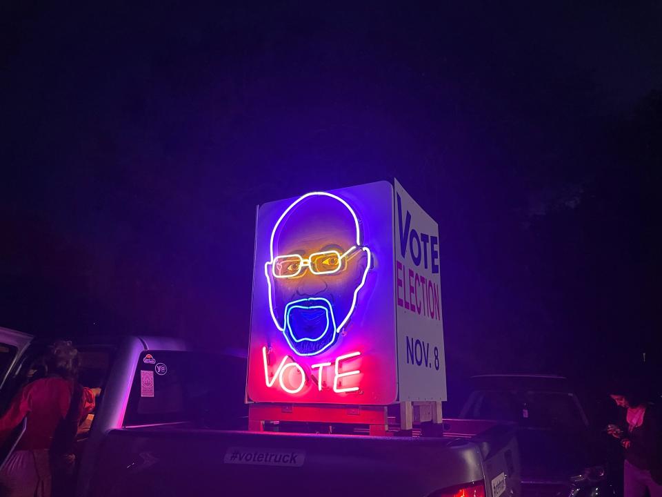 A Warnock supporter carries a neon sign in support of the senator in the back of their truck.