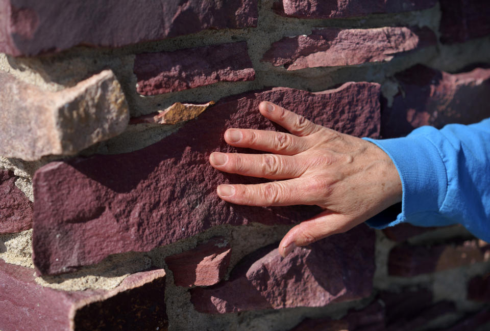 Cindy Pederson grazes her hand across the unique variety of soft pipestone called catlinite used in a pillar outside of the Pipestone National Monument Museum on Wednesday, May 3, 2023, in Pipestone, Minn. Pederson, started learning how to carve from her grandparents six decades ago. (AP Photo/Jessie Wardarski)