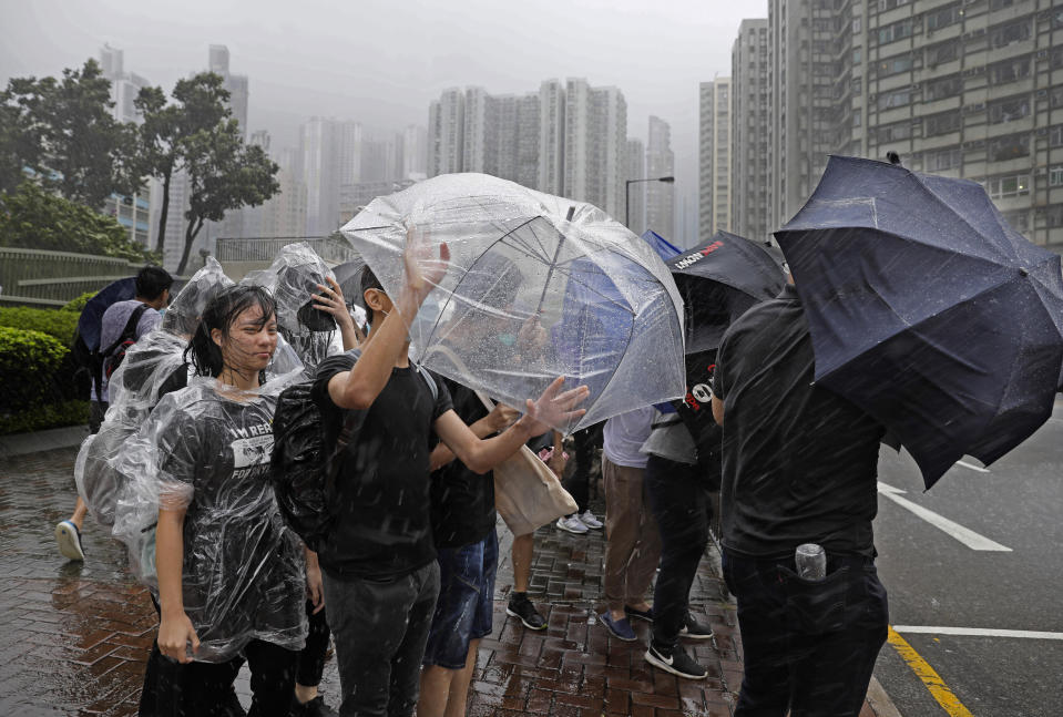 Protesters hold umbrellas against strong winds and heavy rain from Tropical Storm Wipha in Hong Kong Wednesday, July. 31, 2019. The Asian financial center of Hong Kong is shutting down as Wipha approaches, bringing heavy rain and gusts of up to 95 kph (60 mph) in some areas. (AP Photo/Vincent Yu)