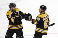 Boston Bruins' Brad Marchand (63) celebrates his open-net goal with Patrice Bergeron (37) during the third period of an NHL hockey game against the Washington Capitals, Sunday, April 18, 2021, in Boston. (AP Photo/Michael Dwyer)