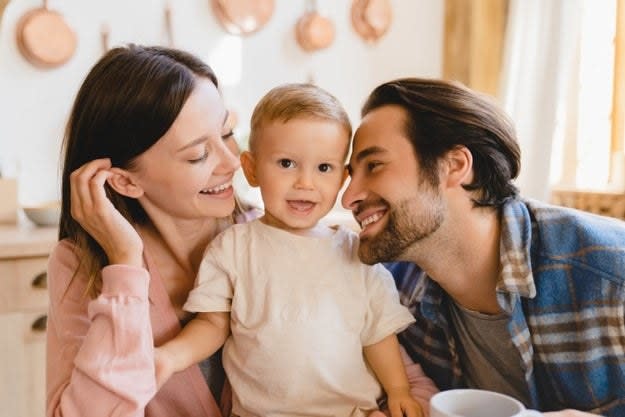 Parents smile with their young child in their kitchen