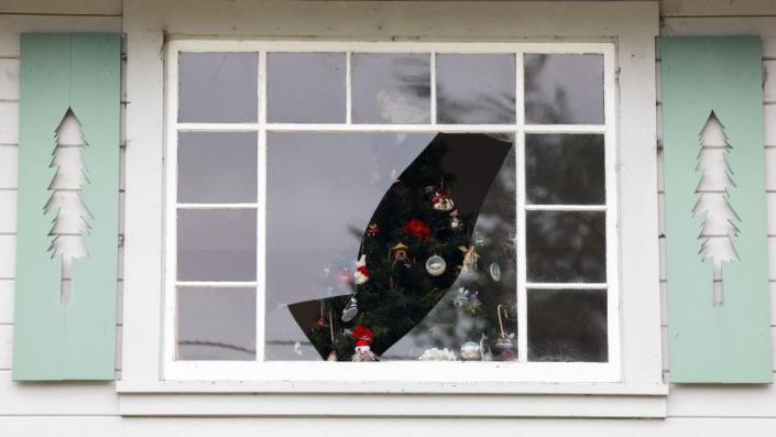 Un árbol de Navidad visto a través de ventanas rotas