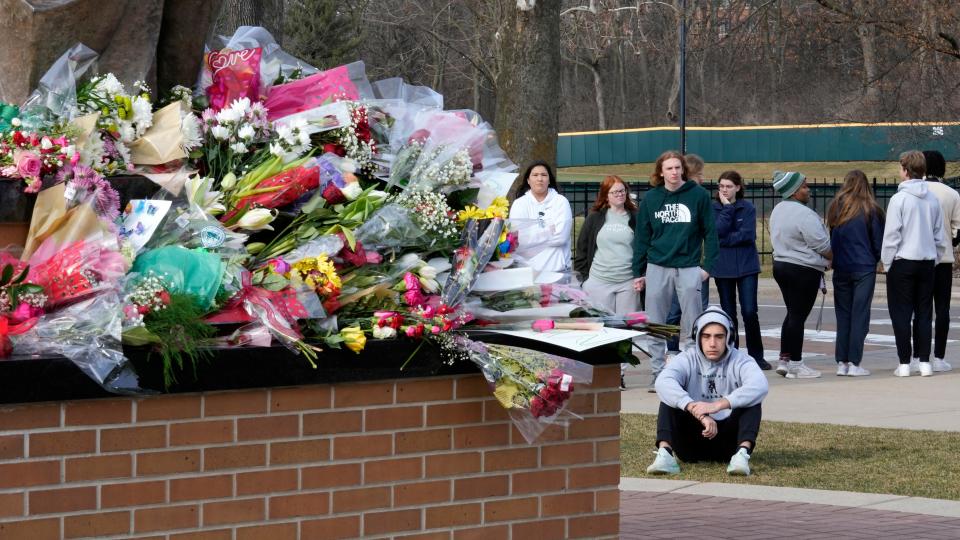 Students gather where flowers are being left at the Spartan Statue on the grounds of Michigan State University, in East Lansing, Michigan.