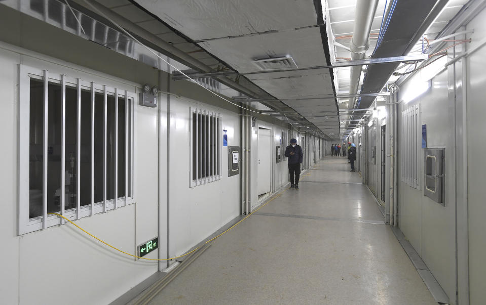 People walk down a corridor at the Huoshenshan temporary field hospital in Wuhan in central China's Hubei Province, Sunday, Feb. 2, 2020. The Philippines on Sunday reported the first death from a new virus outside of China, where authorities delayed the opening of schools in the worst-hit province and tightened quarantine measures in a city that allow only one family member to venture out to buy supplies. (Chinatopix via AP)