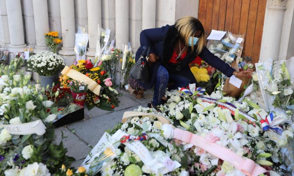 A woman lays flowers in front of the Notre-Dame de l’Assomption Basilica in Nice.