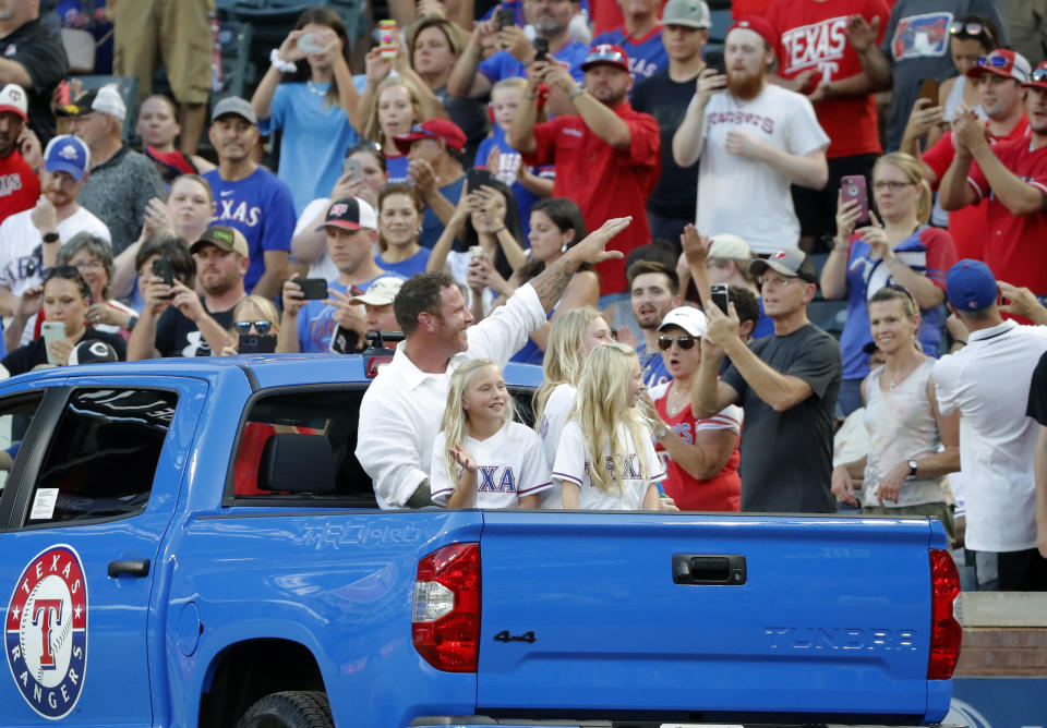 Former Texas Rangers player Josh Hamilton sits in the back of a truck with his daughters as he waves at fans after a club Hall of Fame ceremony before the team's baseball game against the Minnesota Twins in Arlington, Texas, Saturday, Aug. 17, 2019. Hamilton and former Arlington Mayor Richard Greene were inducted in the ceremony. (AP Photo/Tony Gutierrez)