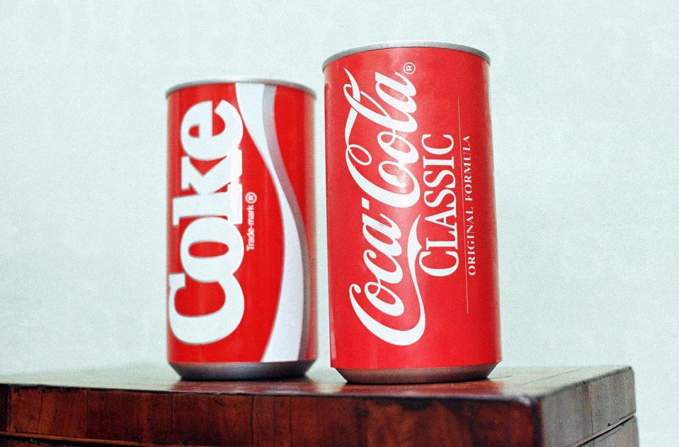 A can of New Coke sits to the left of a can of Coca-Cola Classic against a white background in a photo from 1985.
