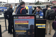 FILE - In this Monday, March 2, 2020 file photo, a health alert for people traveling to China is shown at a TSA security checkpoint at the Denver International Airport in Denver. A steep drop in business travel could be a gut punch to a tourism industry already reeling from the coronavirus outbreak, as big companies like Amazon try to keep employees healthy by banning trips. (AP Photo/Charles Rex Arbogast, File)