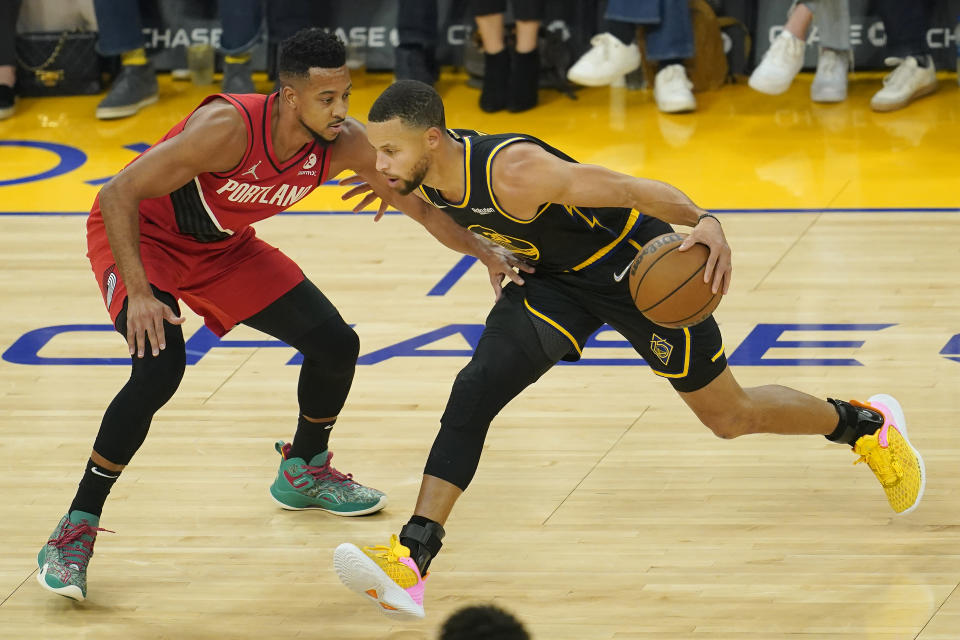 Golden State Warriors guard Stephen Curry, right, drives to the basket against Portland Trail Blazers guard CJ McCollum during the first half of an NBA basketball game in San Francisco, Friday, Nov. 26, 2021. (AP Photo/Jeff Chiu)