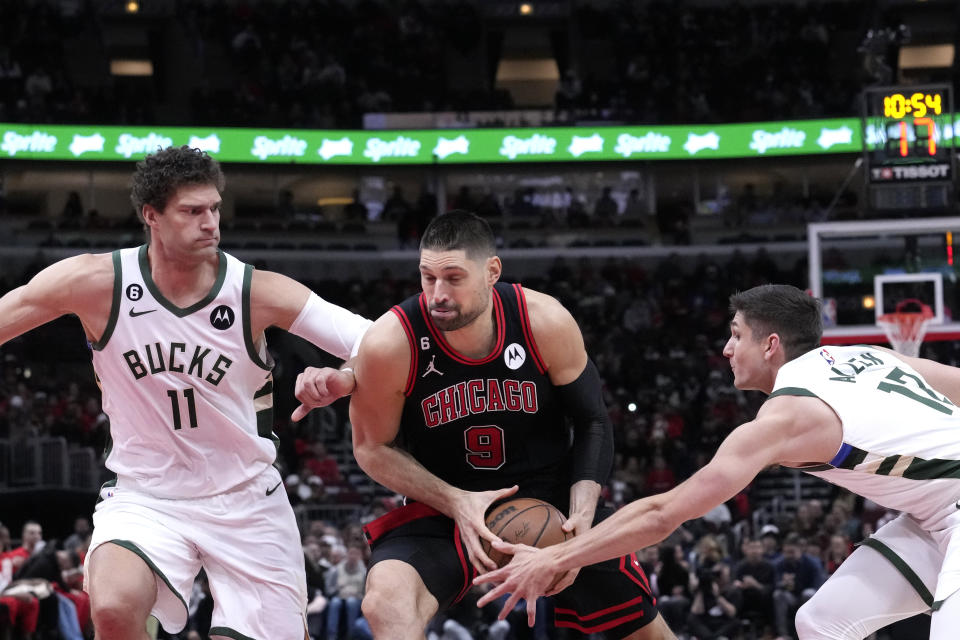 Chicago Bulls' Nikola Vucevic (9) drives to the basket between Milwaukee Bucks' Brook Lopez (11) and Grayson Allen during the first half of an NBA basketball game Thursday, Feb. 16, 2023, in Chicago. (AP Photo/Charles Rex Arbogast)