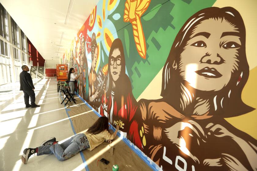 LOS ANGELES, CA - JANUARY 21, 2023 - - Artists Alfonso Aceves, from left, his wife Adriana Carranza, and their daughter Sara Aceves, 27, work on a mural they are painting as a family at Theodore Roosevelt High School in the Boyle Heights in Los Angeles on January 21, 2023. Theodore Roosevelt High School is where Carranza and Accedes met and fell in love over two decades ago. Carranza and Aceves are known as Kalli Arte Collective. (Genaro Molina / Los Angeles Times)