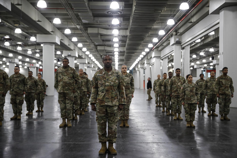 The National Guard stands in formation at the Jacob Javits Center, Monday, March 23, 2020, in New York. New York City hospitals are just 10 days from running out of "really basic supplies," Mayor Bill de Blasio said late Sunday. De Blasio has called upon the federal government to boost the city's quickly dwindling supply of protective equipment. The city also faces a dearth of ventilators to treat those infected by the coronavirus. (AP Photo/John Minchillo)