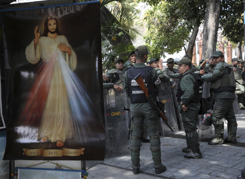 Venezuelan Bolivarian National Guardsmen line up near a Divine Mercy Jesus Christ poster outside the National Assembly in Caracas, Venezuela, Tuesday, Jan. 29, 2019. Venezuela's chief prosecutor on Tuesday asked the country's top court to ban opposition National Assembly President Juan Guaido from leaving the country, launching a criminal probe into his anti-government activities while international pressure builds against President Nicolas Maduro.(AP Photo/Rodrigo Abd)