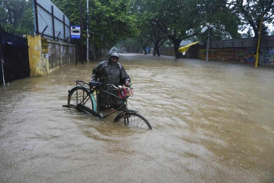 A man pushes his cycle past a flooded street in Chennai, in the southern Indian state of Tamil Nadu, Thursday, Nov. 11, 2021. At least 14 people have died in Tamil Nadu during days of heavy rains, officials said Thursday. Several districts in the state are on high alert, bracing for more torrents as a depression over the southwest Bay of Bengal is set to cross northern Tamil Nadu on Thursday evening. (AP Photo/R. Parthibhan)