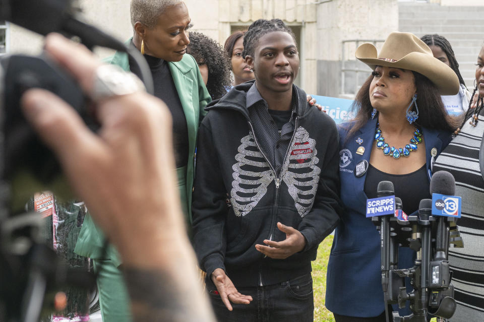 Darryl George, center, makes a comment during a press conference before a hearing regarding George's punishment for violating school dress code policy because of his hair style, Thursday Feb. 22, 2024 at the Chambers County Courthouse in Anahuac, Texas. A judge has ruled that George's monthslong punishment by his Texas school district for refusing to change his hairstyle does not violate a new state law prohibiting race-based hair discrimination. (Kirk Sides/Houston Chronicle via AP)