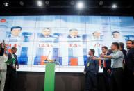 Ukraine's President Volodymyr Zelenskiy reacts next to a screen showing results of exit polls after a parliamentary election at his party's headquarters in Kiev
