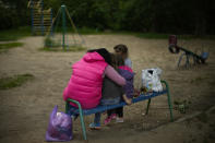 Anna Dyachenko, left, sits with her three daughters Alina, Valeria, and Sonya in a children's playground near their home in Bakhmut, eastern Ukraine, Tuesday, May 24, 2022. The town of Bakhmut has been coming under increasing artillery strikes, particularly over the last week, as Russian forces try to press forward to encircle the city of Sieverodonetsk to the northeast. (AP Photo/Francisco Seco)