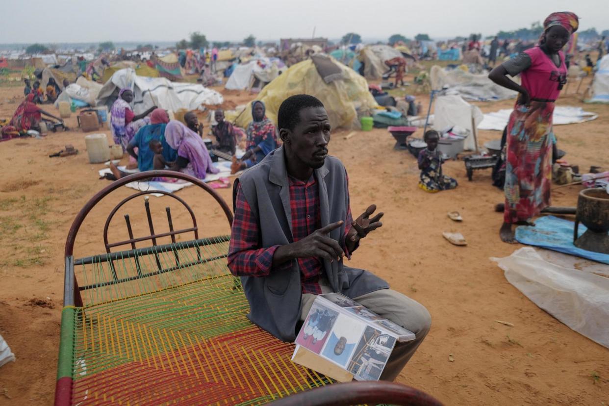 PHOTO: Adam Hassan, who has an album with pictures of his son and father, who he said were killed by the RSF and Arab militias in the West Darfur town of Murnei in June, sits outside his makeshift shelter in Adre, Chad, July 25, 2023. (Zohra Bensemra/Reuters)