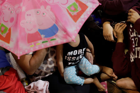 A Honduran family covers their faces to avoid being photographed as they wait to leave with a new caravan of migrants, set to head to the United States, at a bus station in San Pedro Sula, Honduras January 14, 2019. REUTERS/Jorge Cabrera