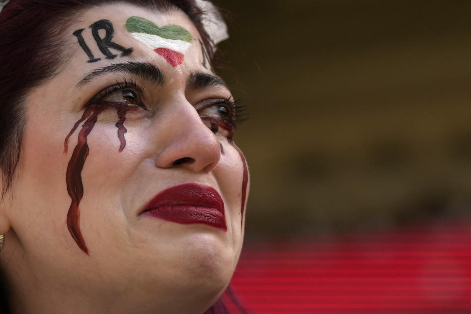 An Iranian woman, name not given, breaks into tears after a member of security seized her flag reading "Woman Life Freedom" before the start of the World Cup group B soccer match between Wales and Iran, at the Ahmad Bin Ali Stadium in Al Rayyan, Qatar, Friday, Nov. 25, 2022. (AP Photo/Alessandra Tarantino)