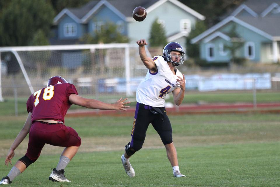 Marshfield quarterback Ashton Fitzgerald Thornton throws a pass under pressure during the prep football jamboree game against Junction City on Aug. 26 at Junction City High School.