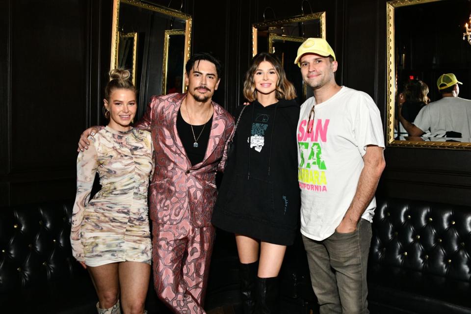 Two women and two men pose in a club with their arms around one another