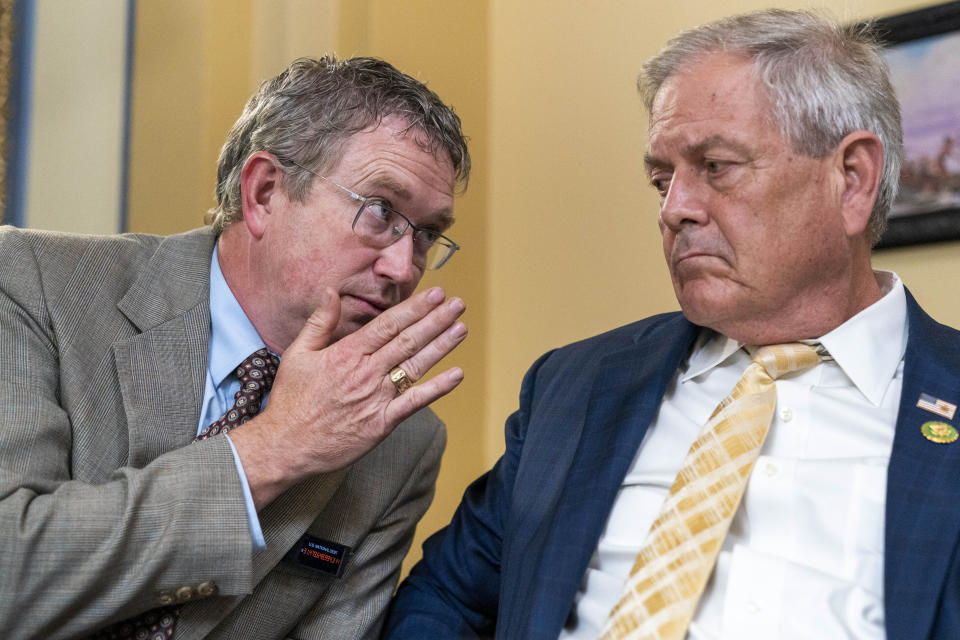 Rep. Thomas Massie, R-Ky., left, wearing a pin simulating the increasing U.S. National Debt, joined at right by Rep. Ralph Norman, R-S.C., both members of the conservative House Freedom Caucus, whispers to Norman as the House Rules Committee meets to prepare the debt limit bill, The Fiscal Responsibility Act of 2023, for a vote on the floor, at the Capitol in Washington, Tuesday, May 30, 2023, at the Capitol in Washington. (AP Photo/Jacquelyn Martin)