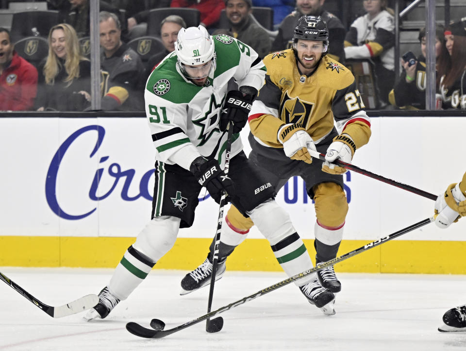 Dallas Stars center Tyler Seguin (91) skates with the puck against Vegas Golden Knights defenseman Shea Theodore during the first period of an NHL hockey game Saturday, Feb. 25, 2023, in Las Vegas. (AP Photo/David Becker)