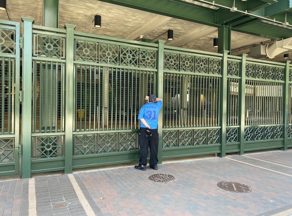 A Cubs fan looks inside Wrigley Field on opening day, where fans were not allowed. (Yahoo Sports)