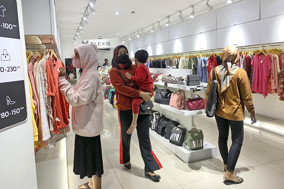 People wearing face mask browse for clothings at a shopping mall in Jakarta, Indonesia, Friday, Dec. 30. 2022. Almost three years after officials announced the first confirmed case of COVID-19 in Indonesia, the country’s leader said Friday they are lifting all coronavirus-related restrictions nationwide. (AP Photo/Tatan Syuflana)