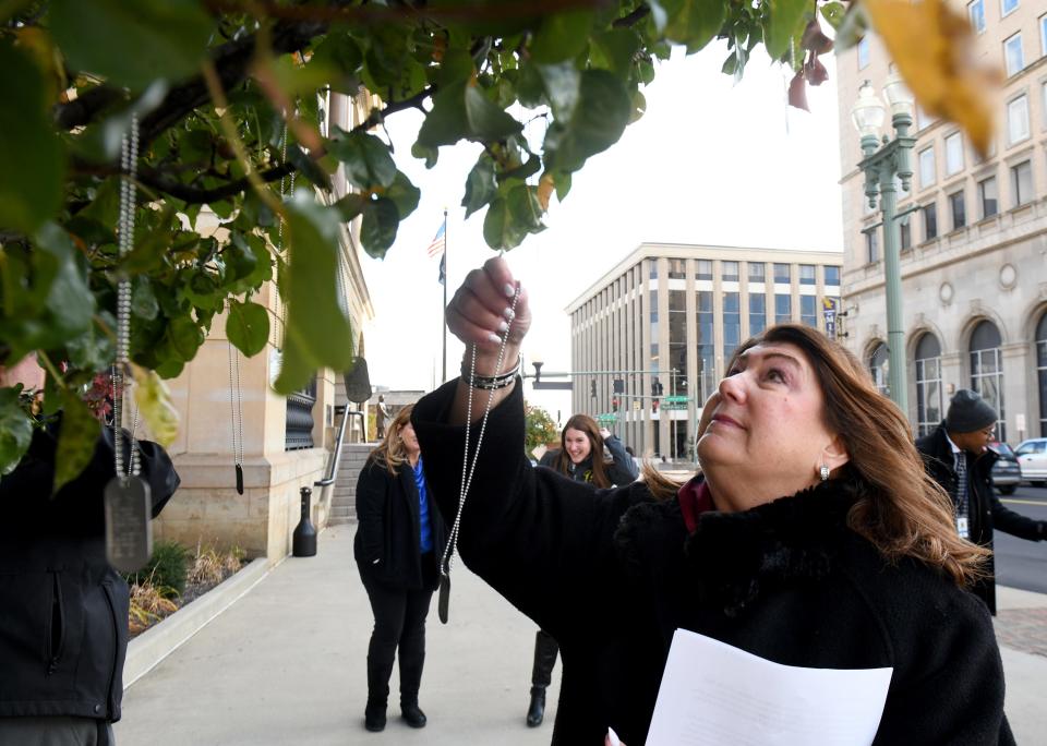 Stark County Common Pleas Judge Taryn L. Heath places a dog tag on the witness tree outside the Stark County Courthouse on Tuesday to remember a veteran who  died by suicide.
