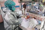 An Afghan nurse observes newborn children who lost their mothers during an attack at a hospital, in Kabul