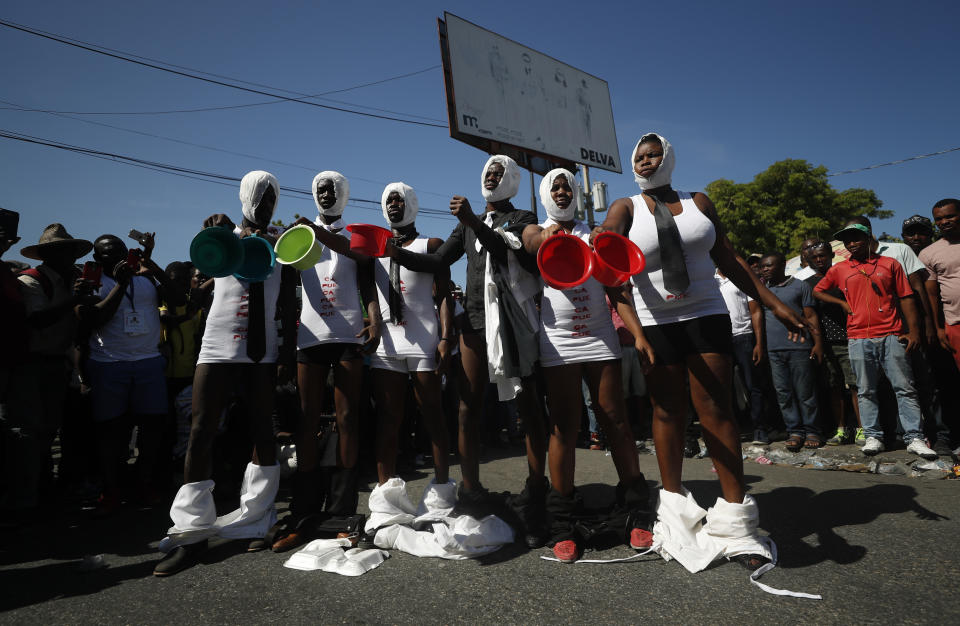 Demonstrators with pants dropped, diapers on heads, and empty bowels in hand perform during a march led by the art community to continue demanding the resignation of Haitian President Jovenel Moise in Port-au-Prince, Haiti, Sunday, Oct. 13, 2019. Protests have paralyzed the country for nearly a month, shuttering businesses and schools. (AP Photo/Rebecca Blackwell)
