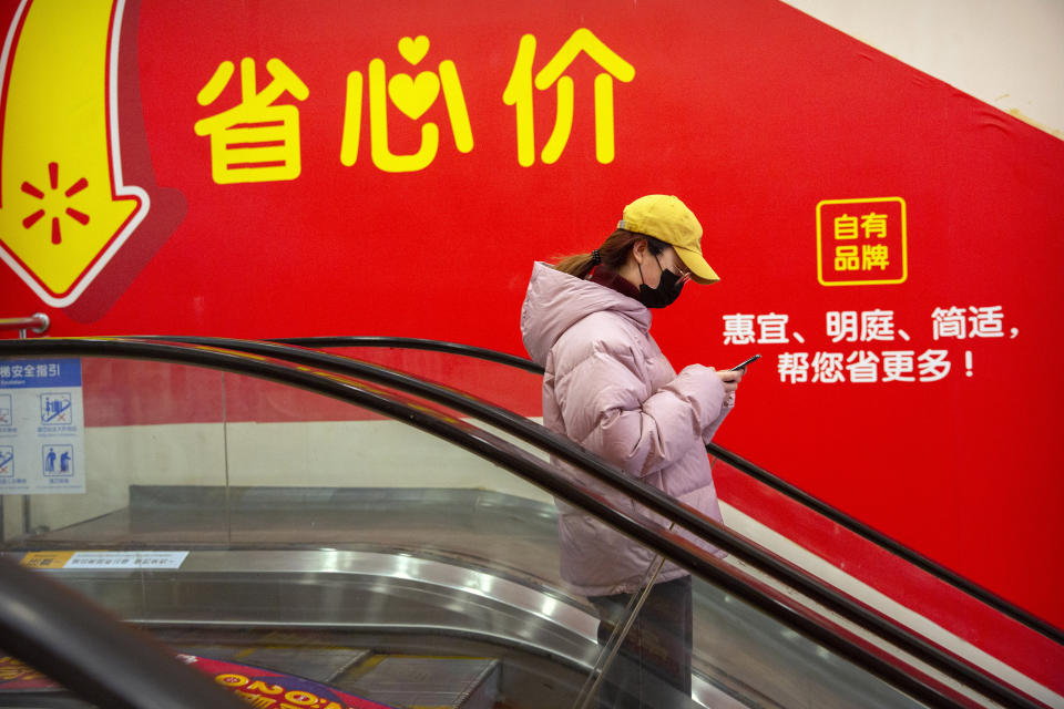 A woman wears a face mask as she rides an escalator at a supermarket in Beijing, Tuesday, Jan. 28, 2020. China's death toll from a new viral disease that is causing mounting global concern rose by 25 to at least 106 on Tuesday as the United States and other governments prepared to fly their citizens out of the locked-down city at center of the outbreak. (AP Photo/Mark Schiefelbein)