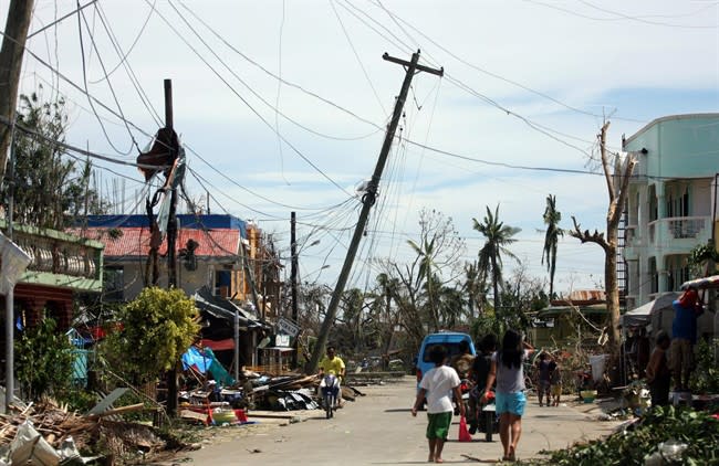 Residents walk past the devastation caused by Typhoon Haiyan, Sunday, Nov. 10, 2013, in Daanbantayan town, north Cebu, central Philippines. Typhoon Haiyan, one of the most powerful storms on record, slammed into six central Philippine islands on Friday, leaving a wide swath of destruction and scores of people dead. (AP Photo/Chester Baldicantos)