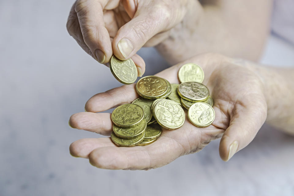 Close-up of senior female hands counting one and two dollar coins in hand.  Selective focus, horizontal, marble background.