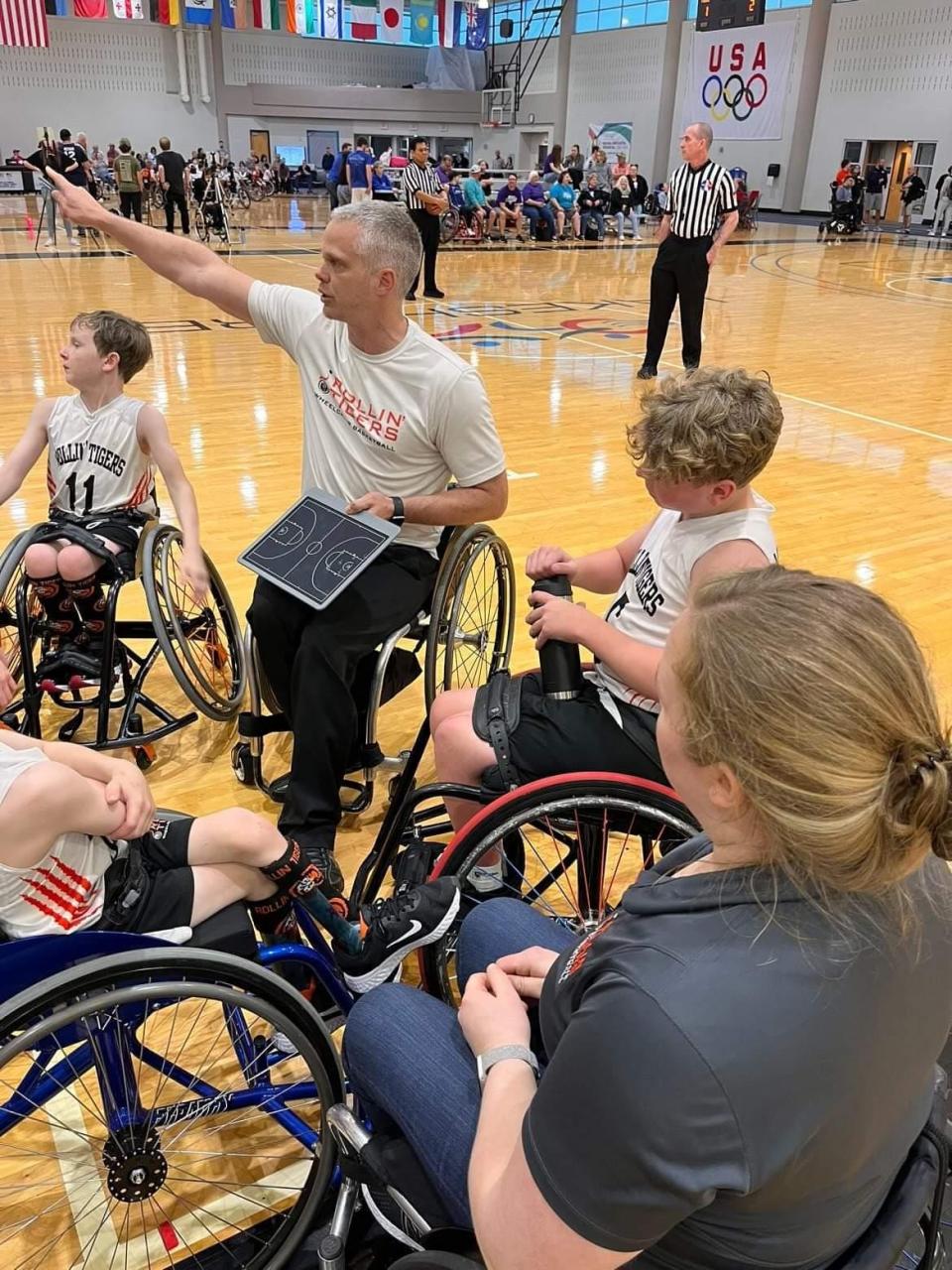 Coaches Lindsey Metz and Jeff Townsend talk to their Roger C. Peace Rollin' Tigers Junior wheelchair basketball team diring a game in Birmingham, Ala.