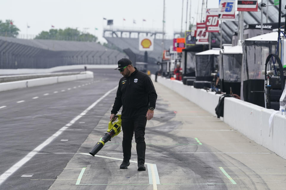 A crew member with Callum Ilott, of England, dries pit lane before practice for the Indianapolis 500 auto race at Indianapolis Motor Speedway, Tuesday, May 16, 2023, in Indianapolis. (AP Photo/Darron Cummings)