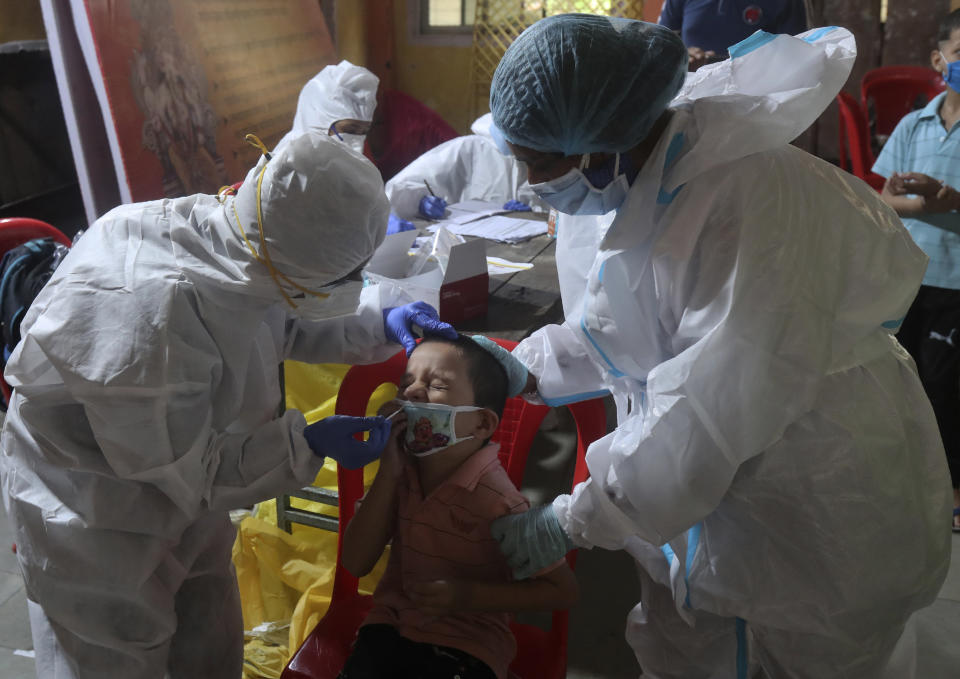 Health workers collect a swab sample to test for COVID-19 in Mumbai, India, Wednesday, Sept. 16, 2020. India's total of coronavirus infections passed 5 million Wednesday, still soaring and testing the feeble health care system in tens of thousands of impoverished towns and villages. (AP Photo/Rafiq Maqbool)