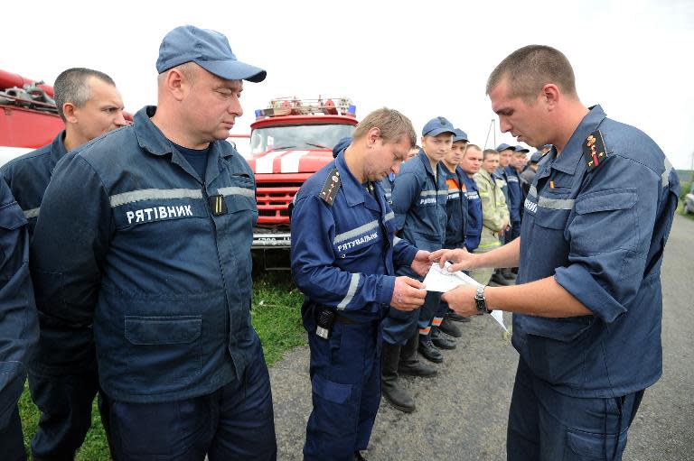 Rescuers receive instructions from a firefighter on July 18, 2014 before searching for bodies at the crash site of Flight MH17 near the town of Shaktarsk, in rebel-held east Ukraine