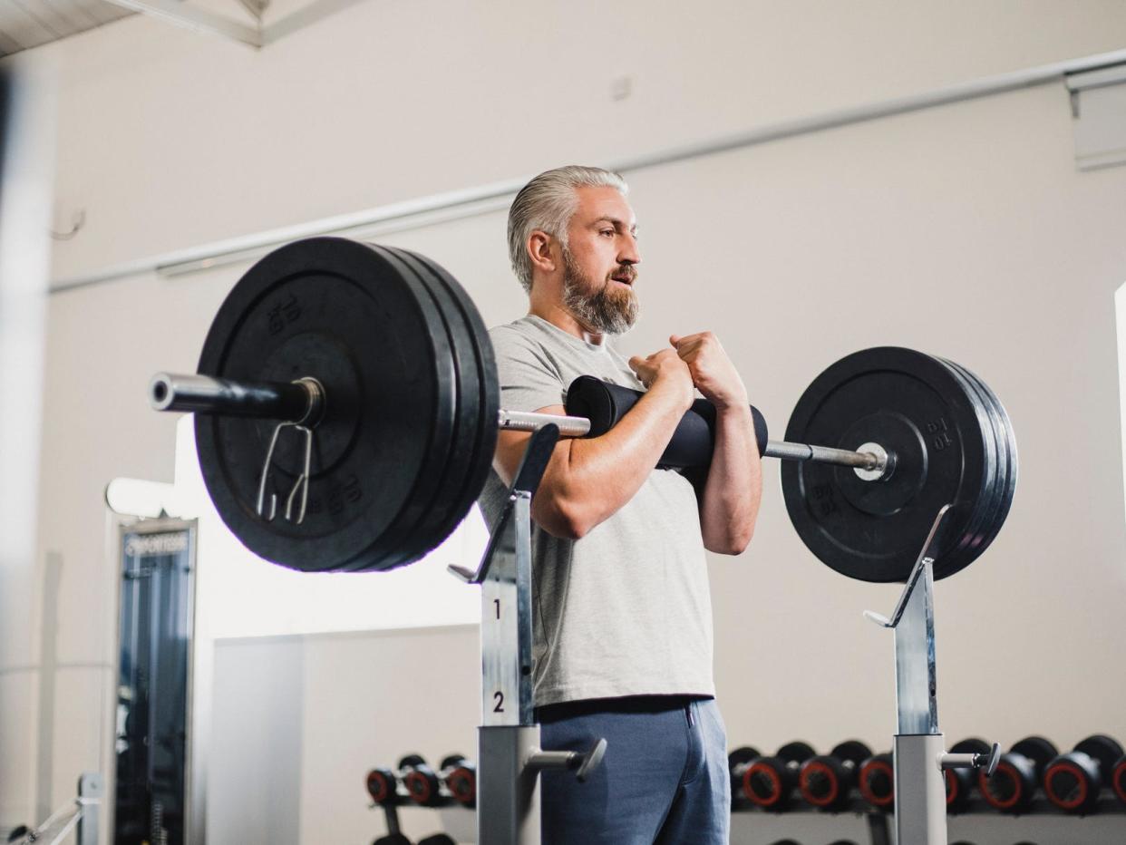 a man working out in a gym lifting weights with a Zercher squat exercise