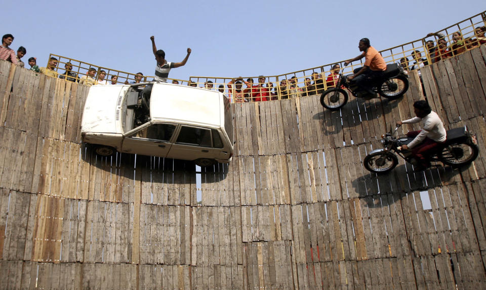 Stuntmen perform on their motorbikes and car on the walls of the "Well of Death" at a fair on the outskirts of Jammu November 28, 2007. The stuntmen earn their livelihood by performing dare-devil stunts by driving their bikes and cars on the walls of the "Well of Death" and attracting a large number of spectators from all walks of life. REUTERS/Amit Gupta